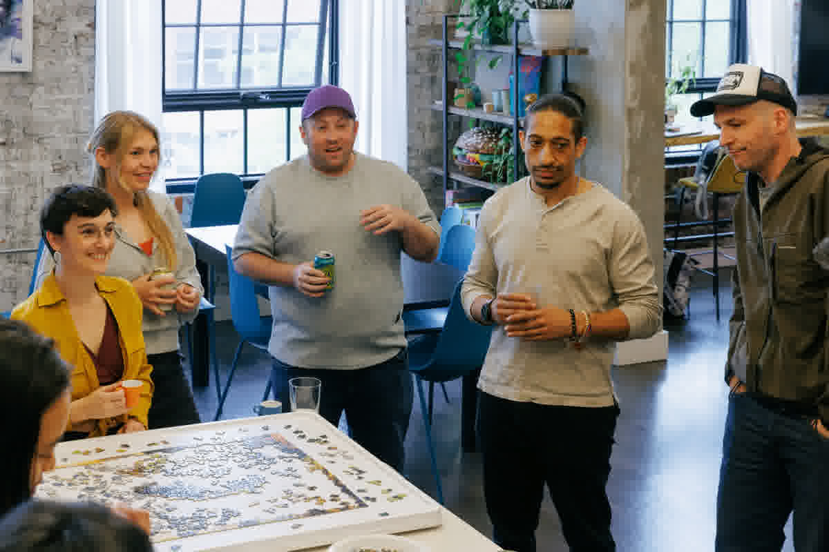 People gathered around a puzzle at Indy Hall, drinks in hand